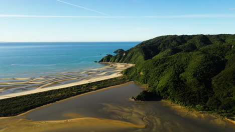 Wainui-beach,-New-Zealand,-aerial-orbit-on-a-sunny-day-with-blue-sky,-travel