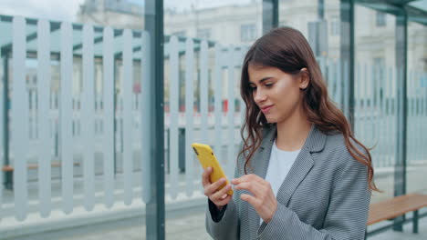 young woman engaged with smartphone at a bus stop