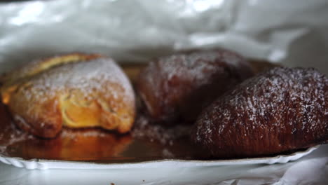 Close-up-hand-of-woman-with-age-spots-picking-up-a-traditional-famous-italian-neapolitan-pastry-called-sfogliatella-napoletana-4k