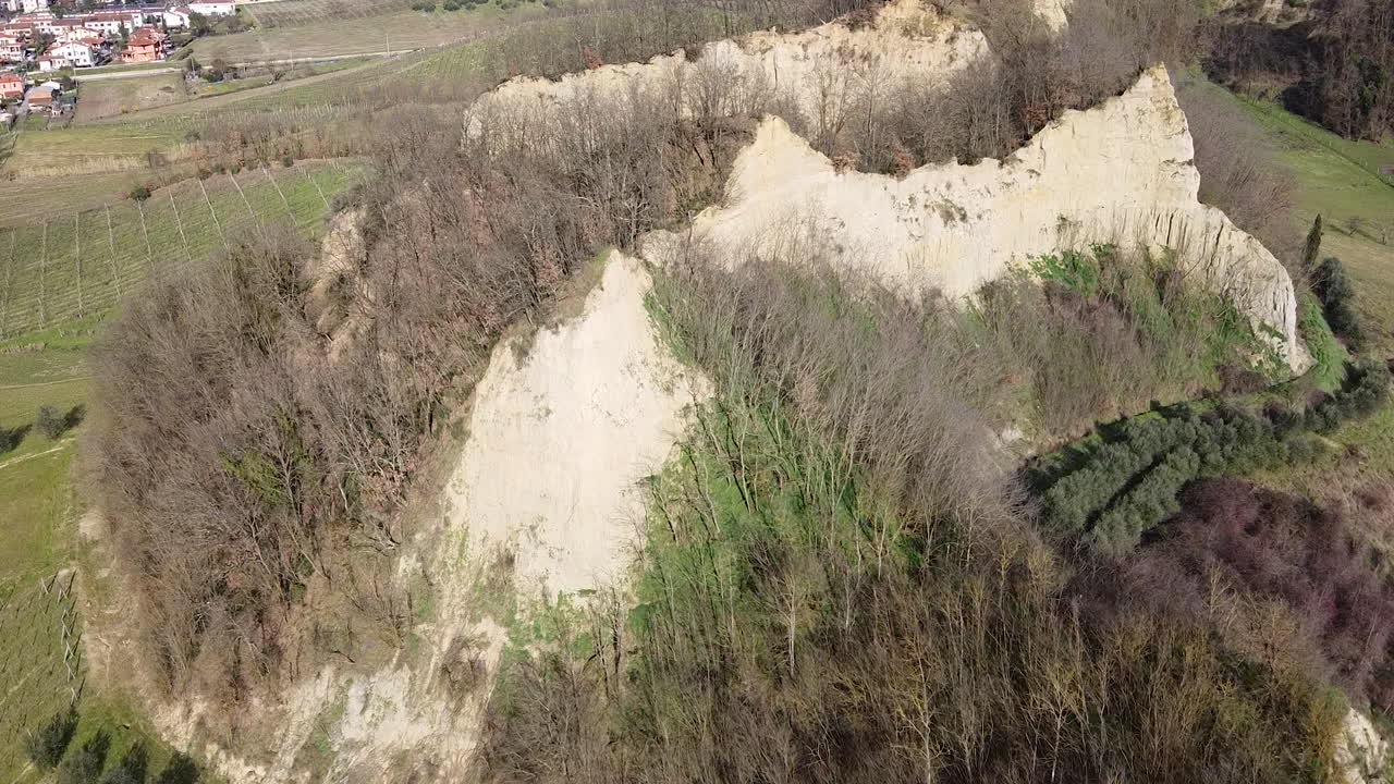 Zooming a specific cliff. Aerial flying drone shot over prehistoric age canyons Le Balze natural reserve near Reggello. Tuscany, Chianti area. Italy. Winter season, partially sunny sunset.