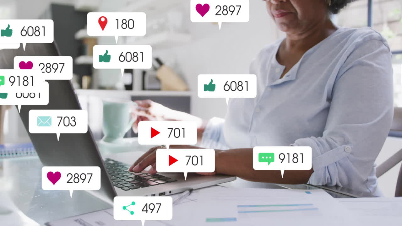 Senior woman typing at glass desk in home office, showing floating social media marketing icons