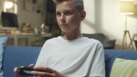 a young boy playing video games on a couch
