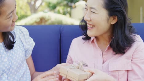 daughter giving gift box to mother in garden 4k