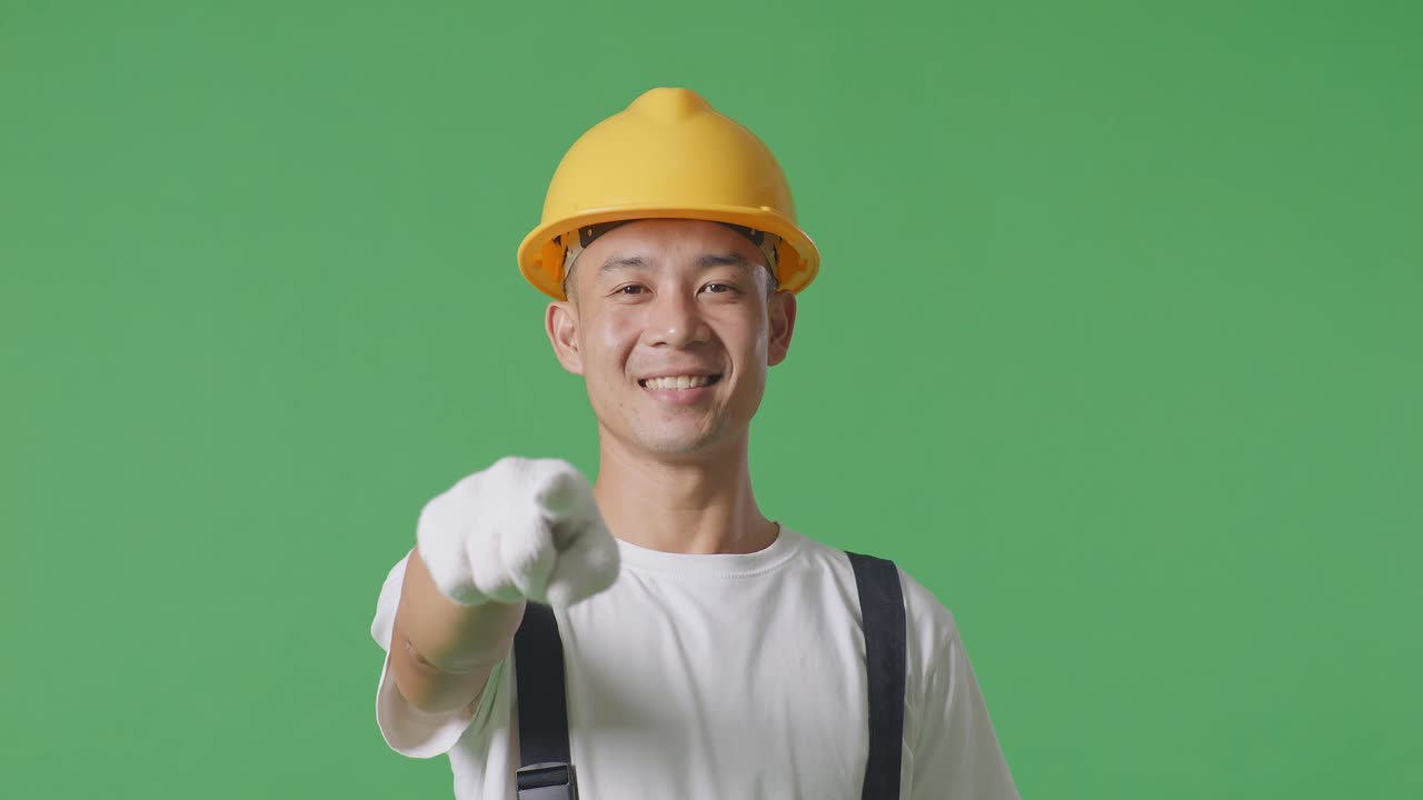 Close Up Of Asian Man Painter Wearing Safety Helmet Smiling And Touching His Chest Then Pointing At You While Standing In The Green Screen Background Studio