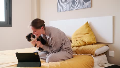 woman with cat on bed using tablet