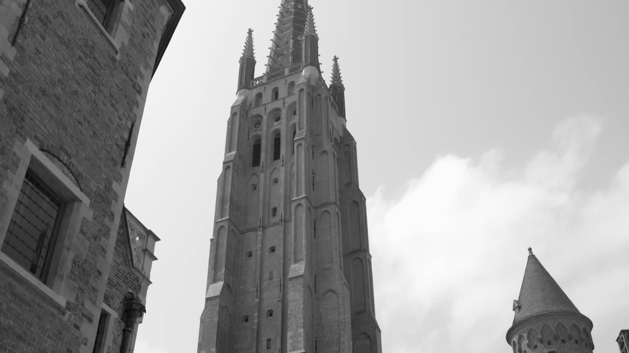 vista en blanco y negro de la iglesia de nuestra señora torre con estilo gótico exterior en bruges, bélgica
