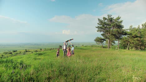 caucasian senior man with his grandchildren in the park while they are flying a kite on a sunny day