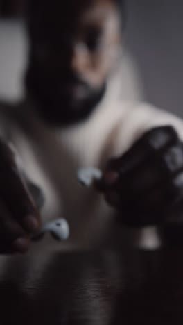 natty black guy picks airpods to listen to music,shallow focus vertical medium shot