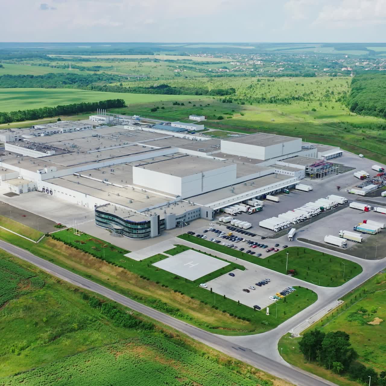 Huge territory of manufacturing in nature. Panoramic view of industrial plant in the middle of green fields. Aerial view.