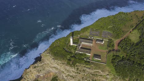 top-down drone footage of a lighthouse on the edge of dramatic cliffs with the atlantic ocean in the background, são jorge island, the azores, portugal