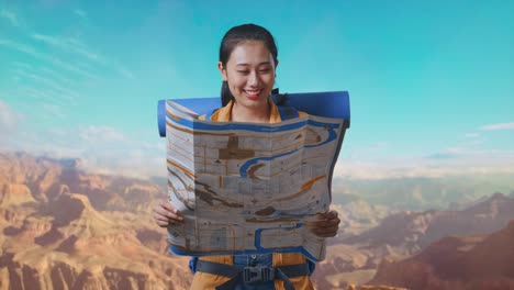 asian female hiker with mountaineering backpack looking at the map then smiling to camera while traveling at the top of mountain
