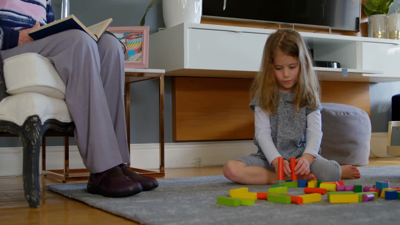 Girl playing with building blocks in living room 4k
