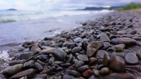 beautifully shaped rocks laying on shore of lake taupo in new zealand, slowmo