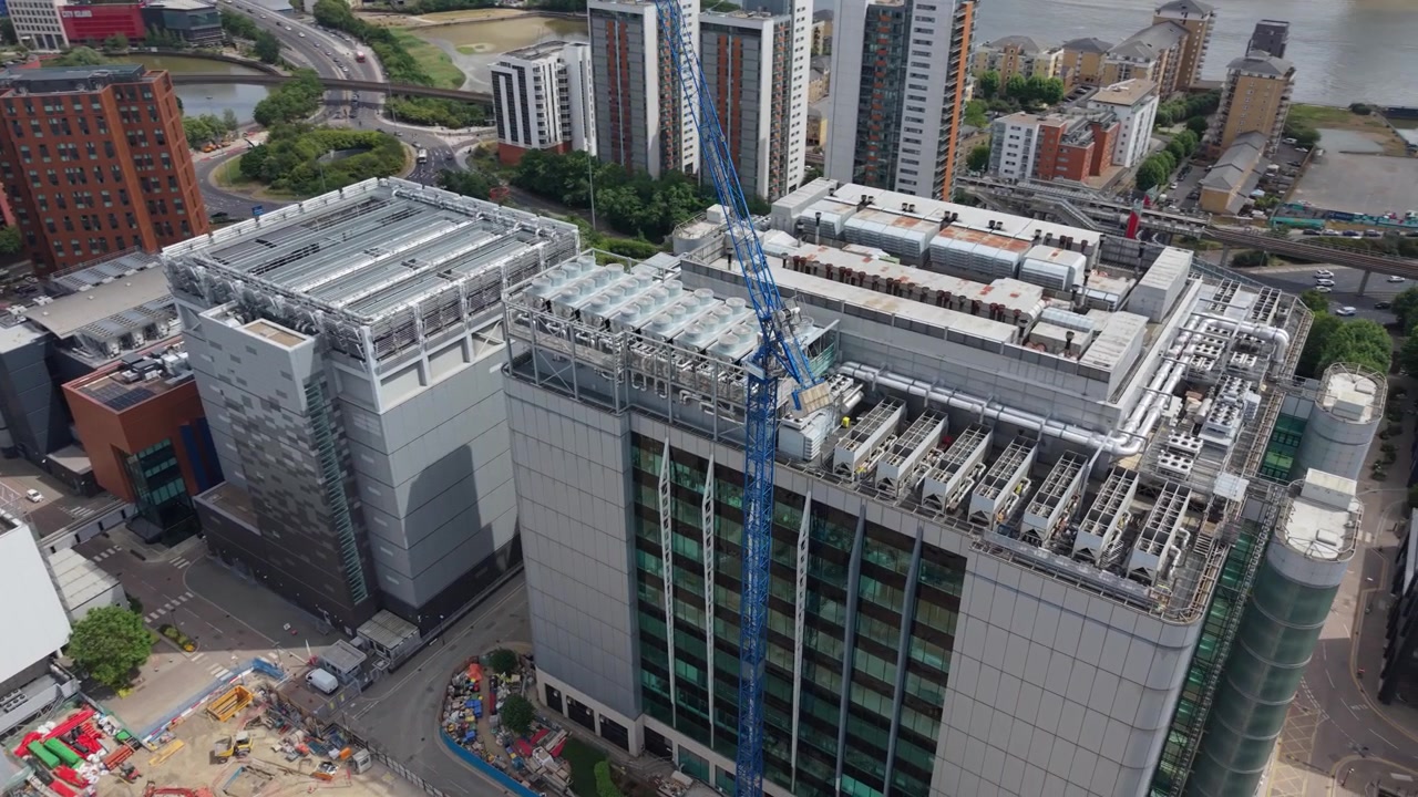 Una perspectiva aérea muestra un moderno Centro de Datos en construcción en un vibrante paisaje urbano. Grúas se alzan sobre el edificio y las obras de cimentación activas.