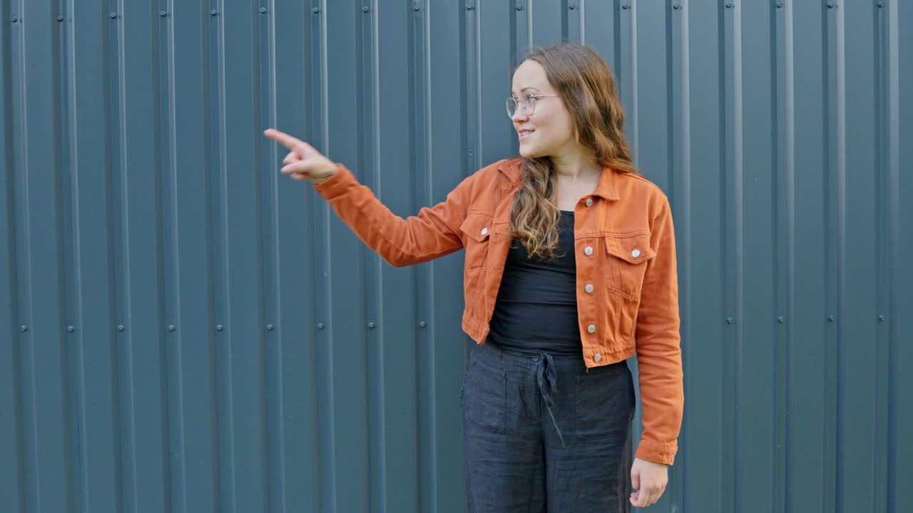 mujer mira a la izquierda sonriendo sosteniendo los pulgares hacia arriba para la aprobación asintiendo con la cabeza