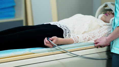 patient in the hospital. woman is laying in magnetic resonance image device. nurse preparing the patient before doing tomography procedure.