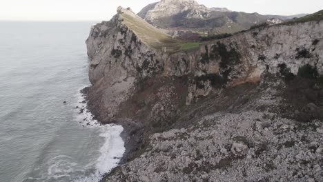 rocky cliff washed by wavy endless sea on cloudy day. cantabria, spain