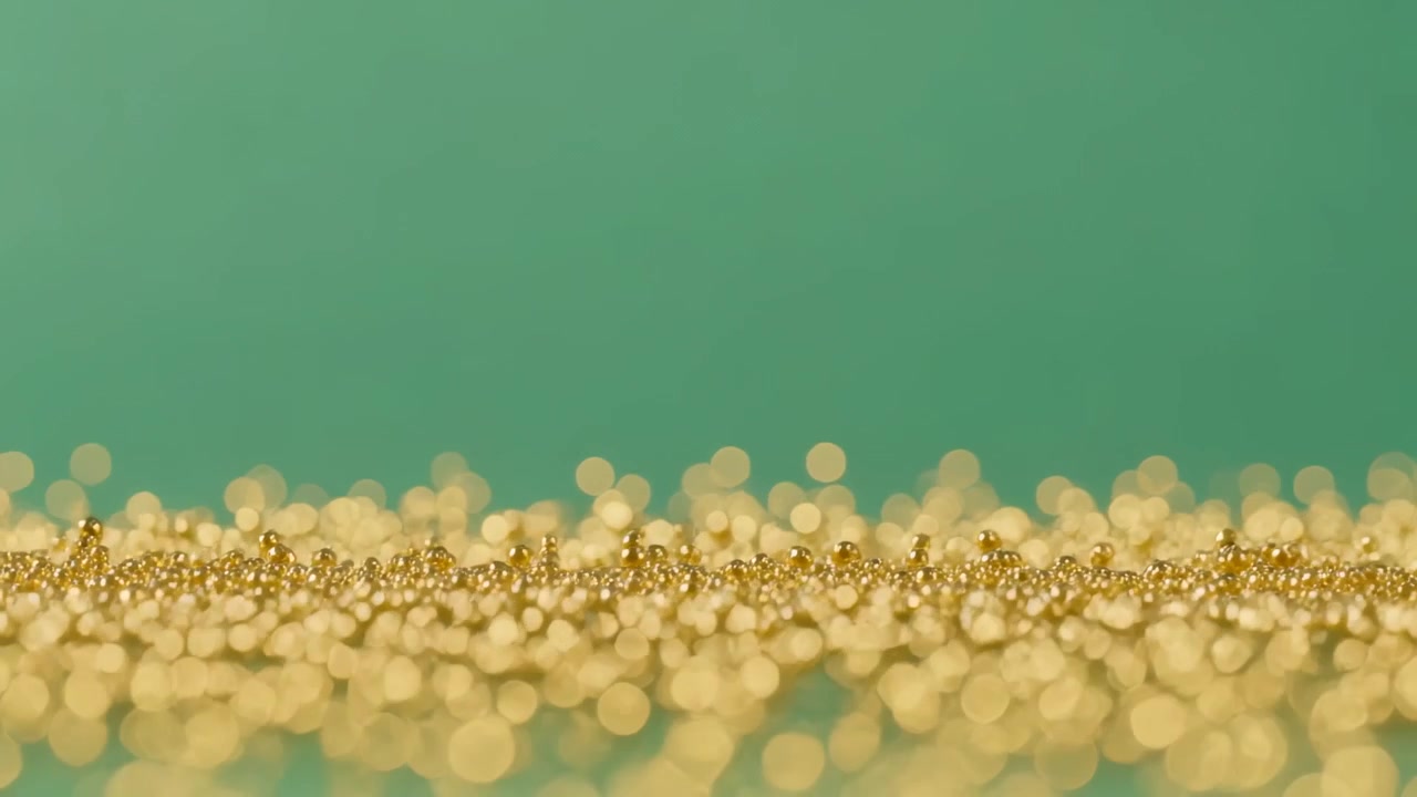 Stüdyo ışığı altında parlak yüzeyde kayan parlayan altın boncuklar ve bokeh diskleri, deniz mavisi fon.
