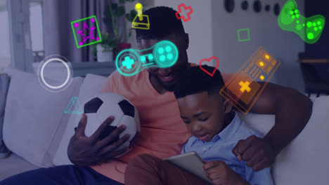 animation of game media icons over smiling father and son using tablet on couch at home