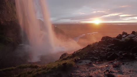 iceland waterfall with sunset in the background in slow motion