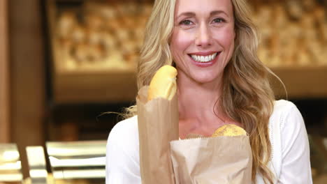 una rubia sonriente sosteniendo bolsas de papel