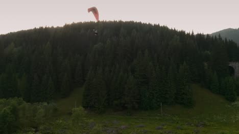aerial drone shot of a paraglider over a forest near chmarocsky viaduct in low tatras in slovakia, europe.