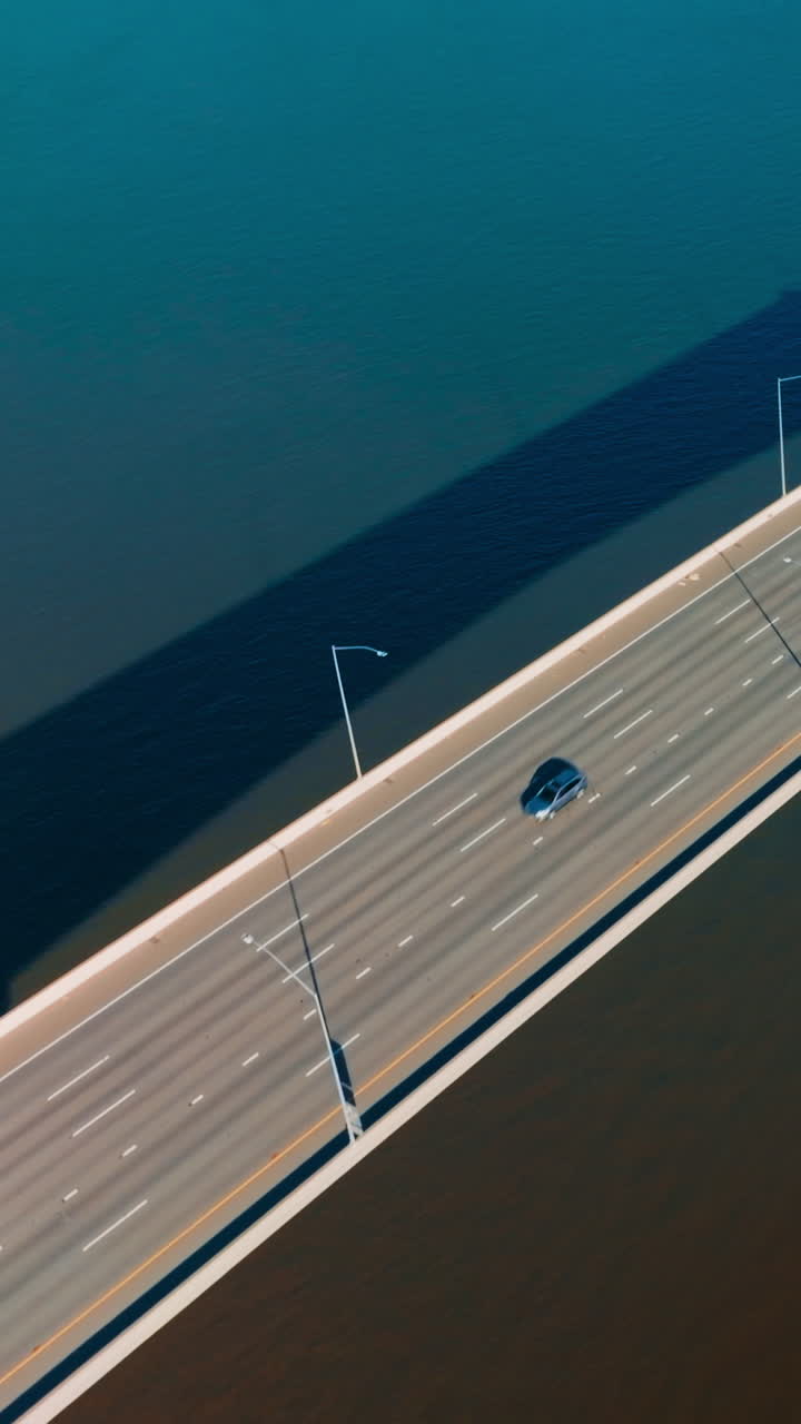 Approaching and flying over the bridge connecting Martinez to Benicia. Cars moving by the bridge in same direction. Top view. Vertical video