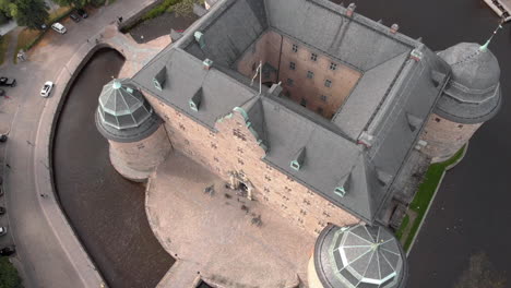 toma en gran angular de un dron que sobrevuela y se desplaza hacia abajo en el castillo de örebro en suecia