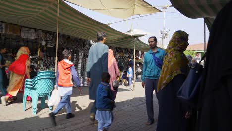 lively islamabad market scene featuring people enthusiastically haggling and shopping for groceries from colorful street vendors and stalls.