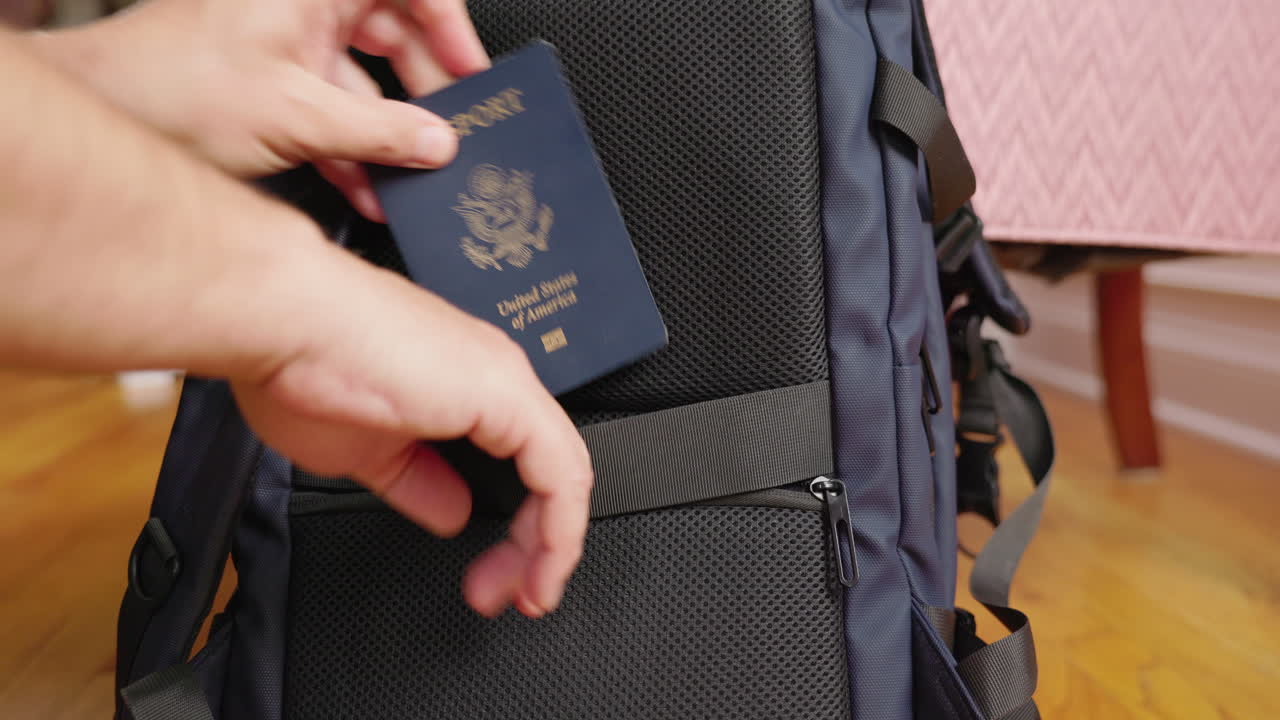 Primer plano de una mano guardando un pasaporte en el bolsillo de seguridad de una mochila.
