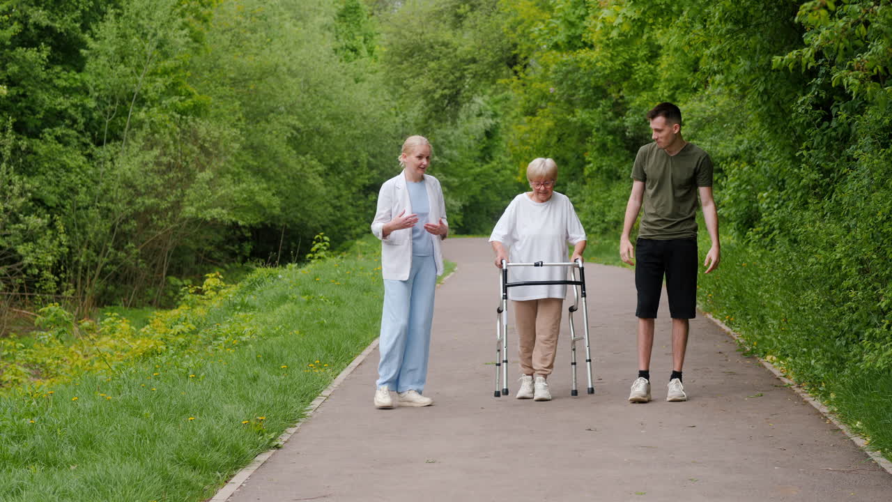 Elderly Woman with Walker Being Assisted by Two Young People in a Park