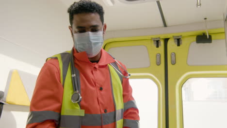 paramedic wearing facial mask fastening the seat belt of a patient lying on the stretcher inside an ambulance