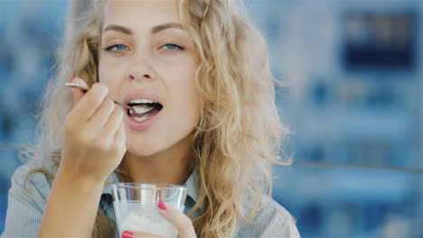 attractive young woman eating ice cream in cafe smiling at the camera