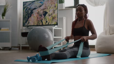 athlete with black skin in sportswear exercising body muscle using fitness elastic