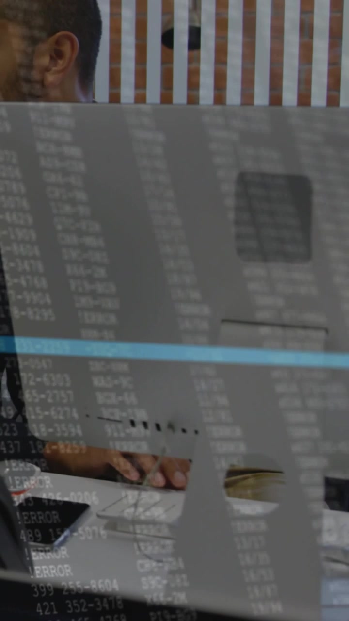 Vídeo vertical: Monitor com sobreposição mostrando homem debruçado e digitando código de depuração para a equipe.