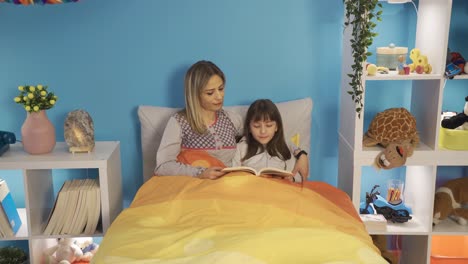 la niña está leyendo un libro en la guardería. madre hija amor.