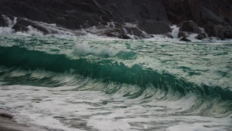 poderosas olas se estrellan contra las rocas y se derraman en la orilla arenosa