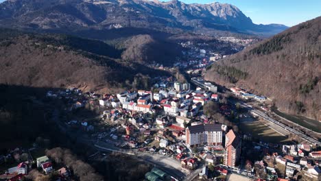 aerial birds eye shot of small mountain city of sinaia during sunny day in romania - tilt up shot