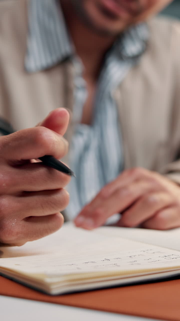 Primo piano di un uomo che scrive su un taccuino e si strofina il polso