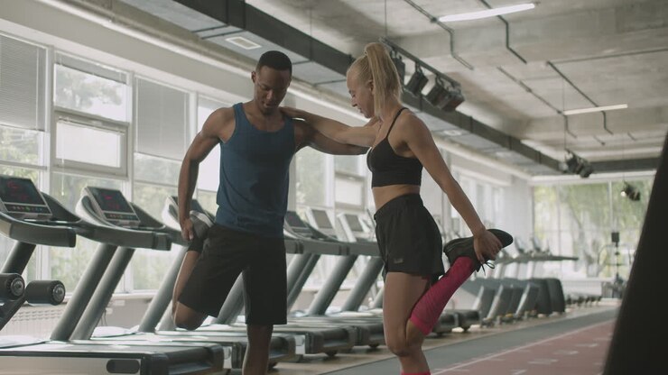 Vorderansicht einer kaukasischen Trainerin und eines athletischen afroamerikanischen Mannes im Fitnessstudio.