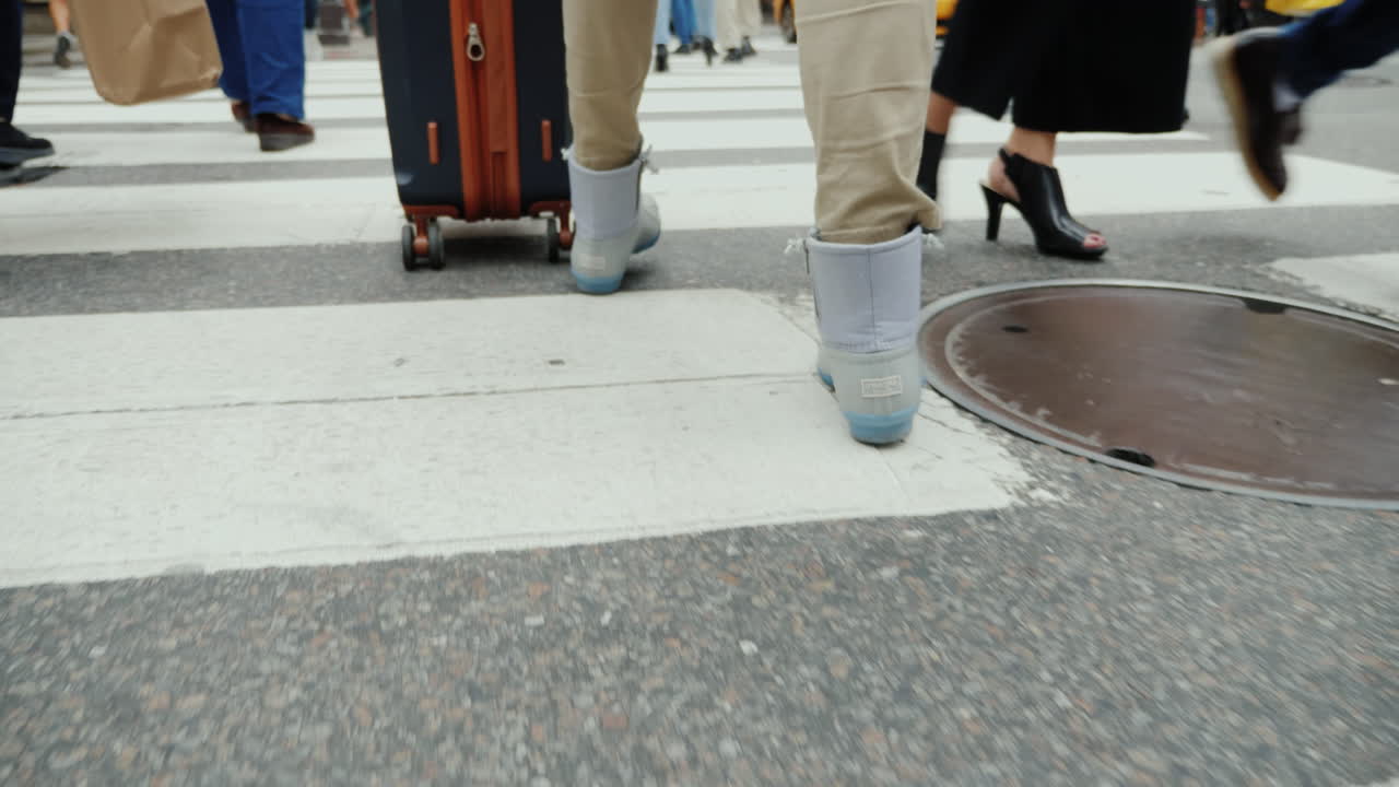 A Person With A Bag On Wheels Goes Down The Busy Sidewalk Of Manhattan In New York Only Legs Are Vis