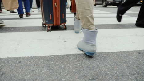 A-Person-With-A-Bag-On-Wheels-Goes-Down-The-Busy-Sidewalk-Of-Manhattan-In-New-York-Only-Legs-Are-Vis