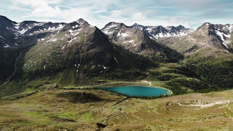 Turquoise-mountain-lake-surrounded-by-partly-snow-covered-alpine-terrain,-on-the-border-between-Italy-and-Austria