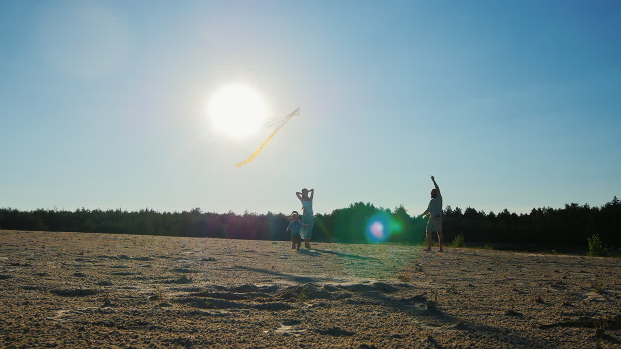 молодая семья из четырех человек, отдыхающая вместе - запускает воздушного змея