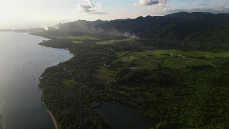 panoramic view of tropical coastline, lush valleys, and mountainous background at island province catanduanes, philippines - aerial flyover shot