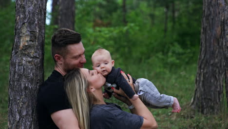 happy mom holding her newborn son above head. happy parents look at their child with love and adoration. nature backdrop.