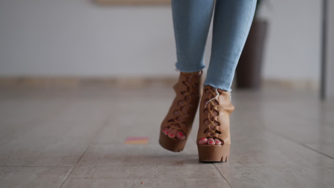 cerca de los pies de la mujer caminando hacia la cámara con tacones altos y jeans en cámara lenta