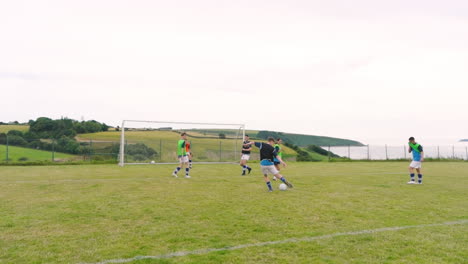 Male and female soccer players, passing and shooting at goal on pitch, slow motion, copy space