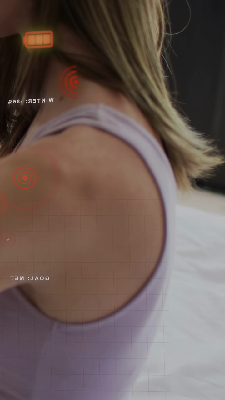 Vertical video: Woman adjusting posture shoulder rotating HUD tracking battery icon, rings for tech