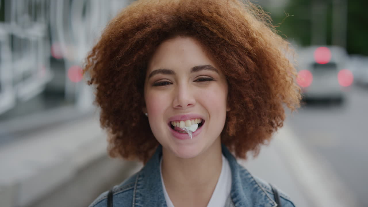 ritratto di una giovane donna giocosa che soffia una gomma da masticare dolce che si diverte una studentessa carina funky afro in una strada urbana